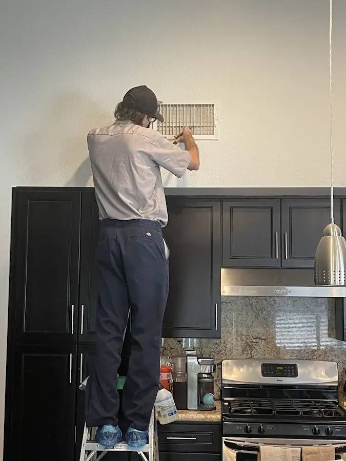 Technician inspecting an air vent during HVAC service in Chapel Hill